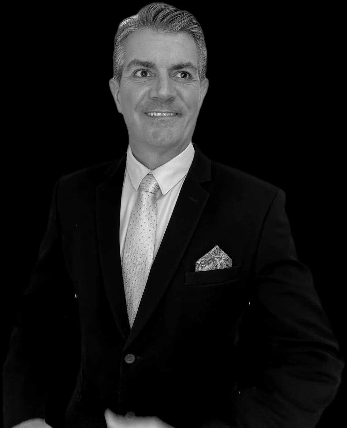 Tom West in a suit and pink tie, smiling